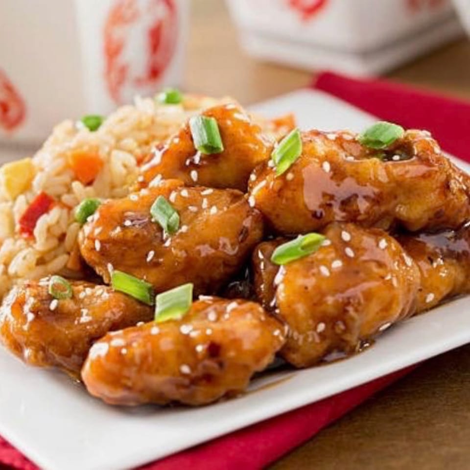 Red Lotus Noodle House's sesame chicken with fried rice, garnished with green onions.