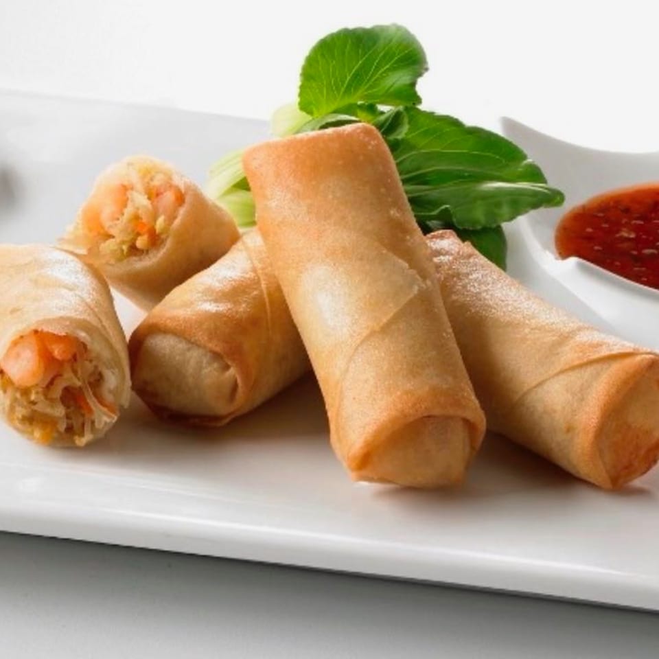 Crispy golden spring rolls with shrimp and vegetables, served with a side of sweet chili sauce and bok choy.