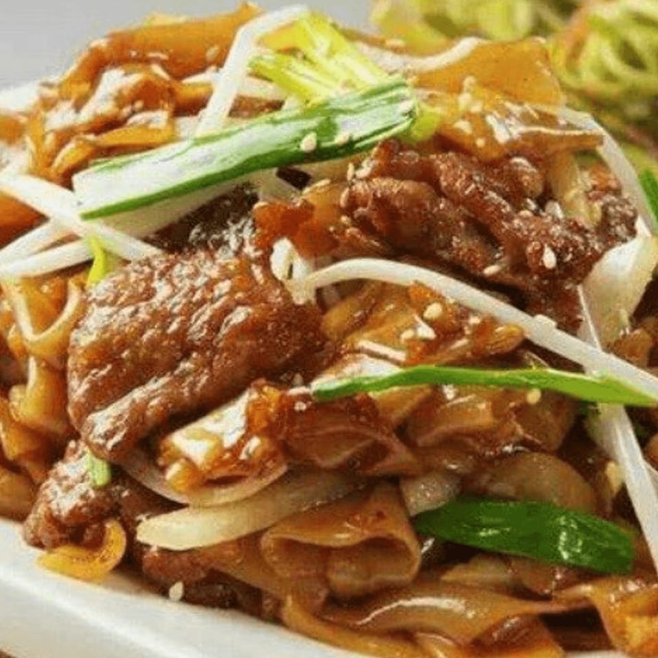 Close-up of Red Lotus Noodle House's beef chow fun with wide noodles, beef, and green onions.